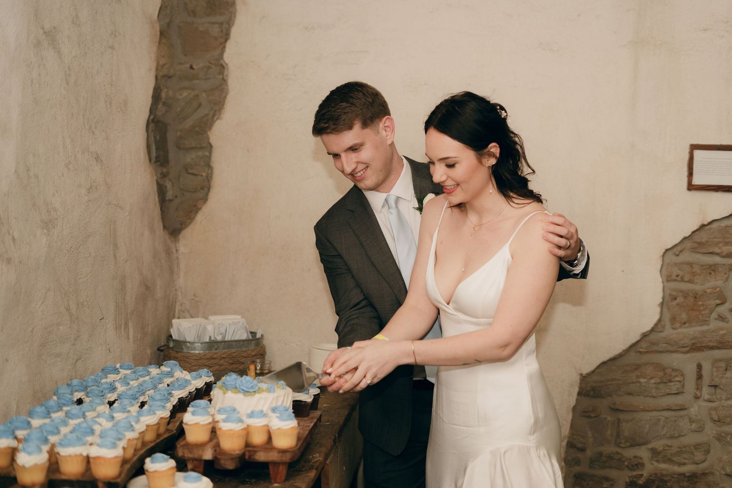 A couple in wedding attire cuts their wedding cake together at their reception.
