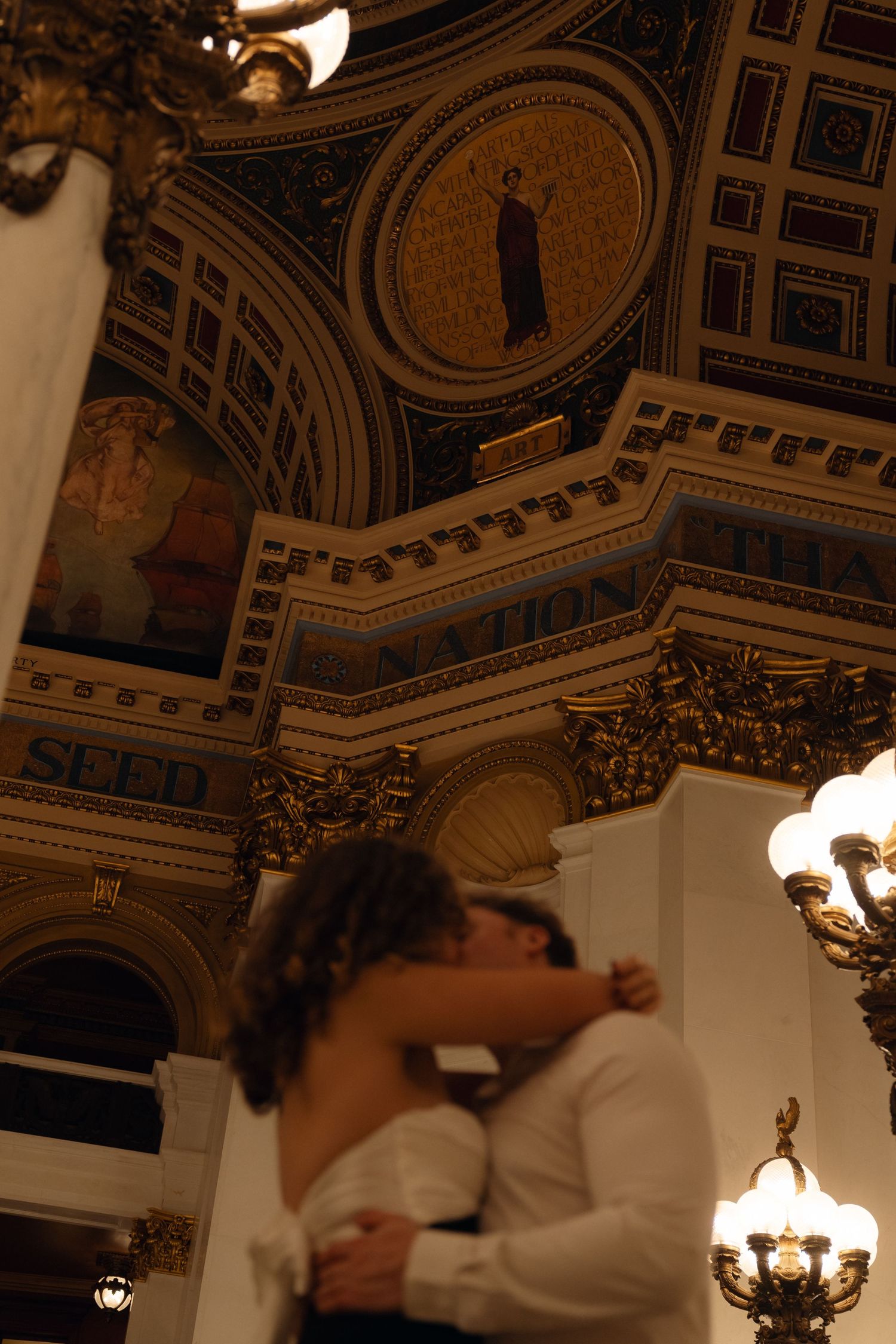 Ornate ceiling with decorative moldings and chandeliers in a historic building interior.