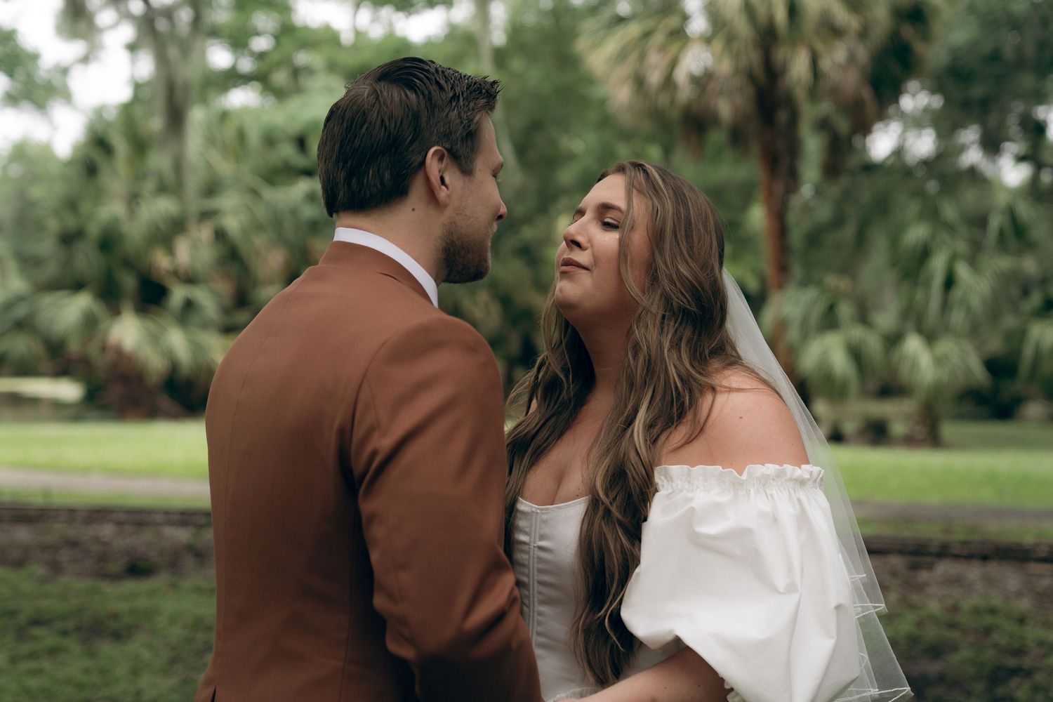 A couple shares romantic moments in a lush outdoor garden setting during their wedding photoshoot. New Orleans