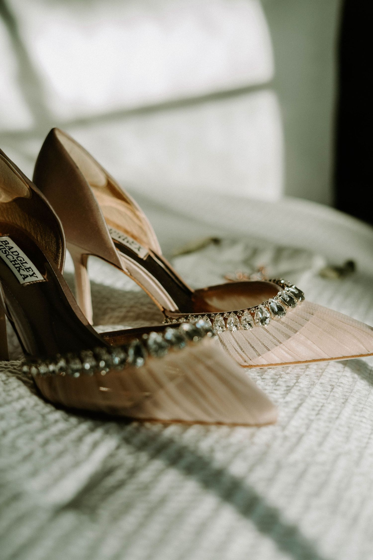 Elegant bridal shoes with crystal embellishments photographed on white fabric.