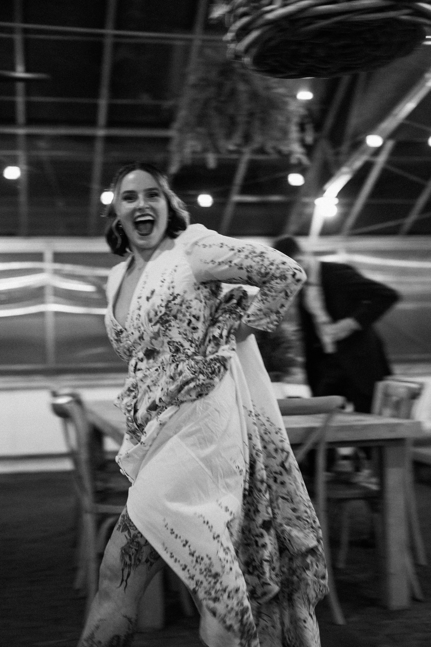 A joyful dancing moment in a floral dress captured in black and white photography.