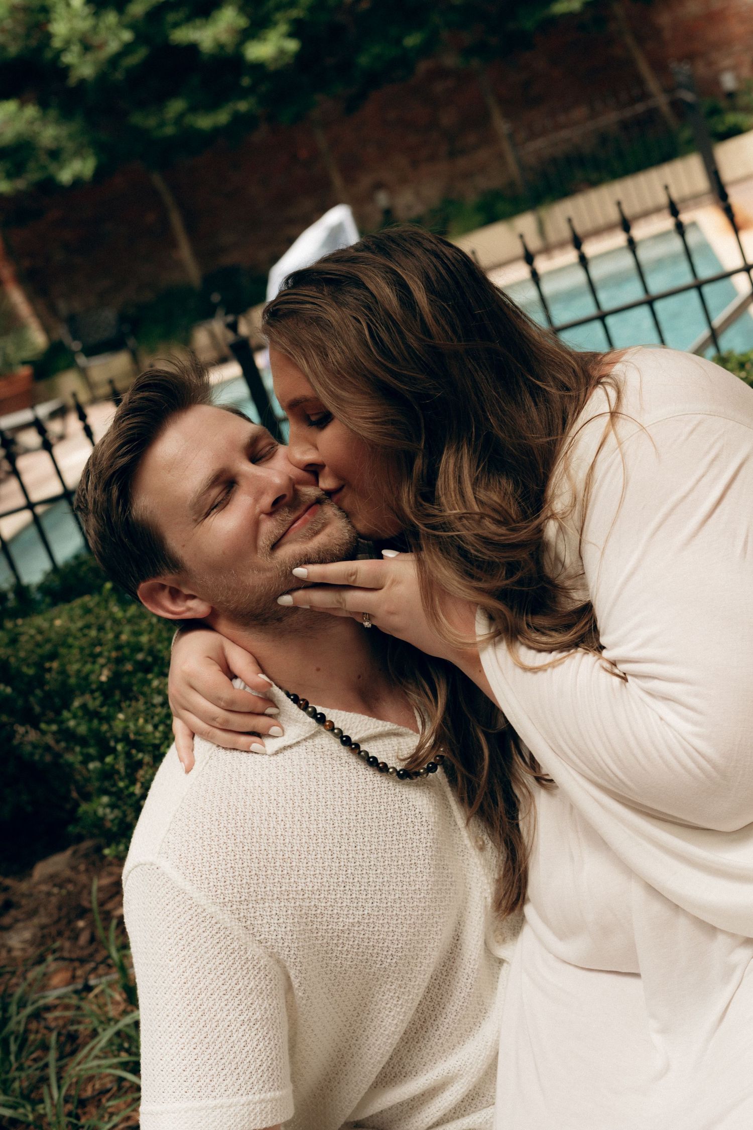 A couple in matching white sweaters share tender romantic moments by a swimming pool in a progressive photo series.