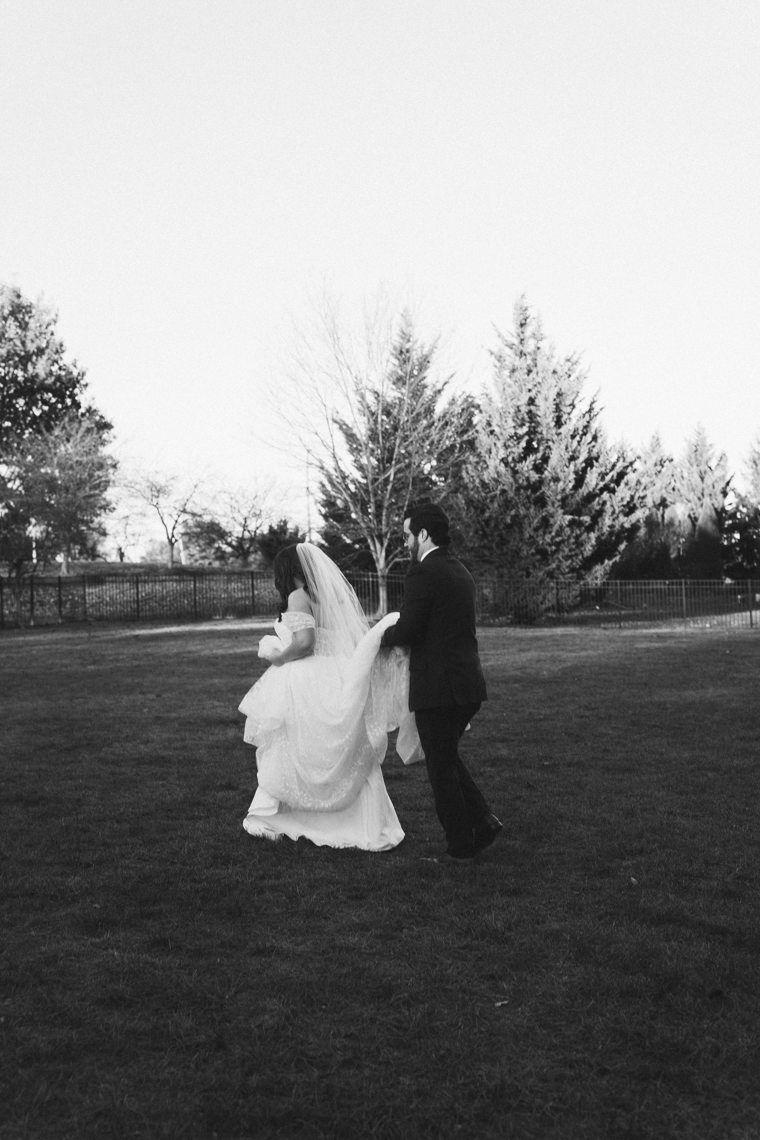 Black and white portrait of couple dancing in garden setting.