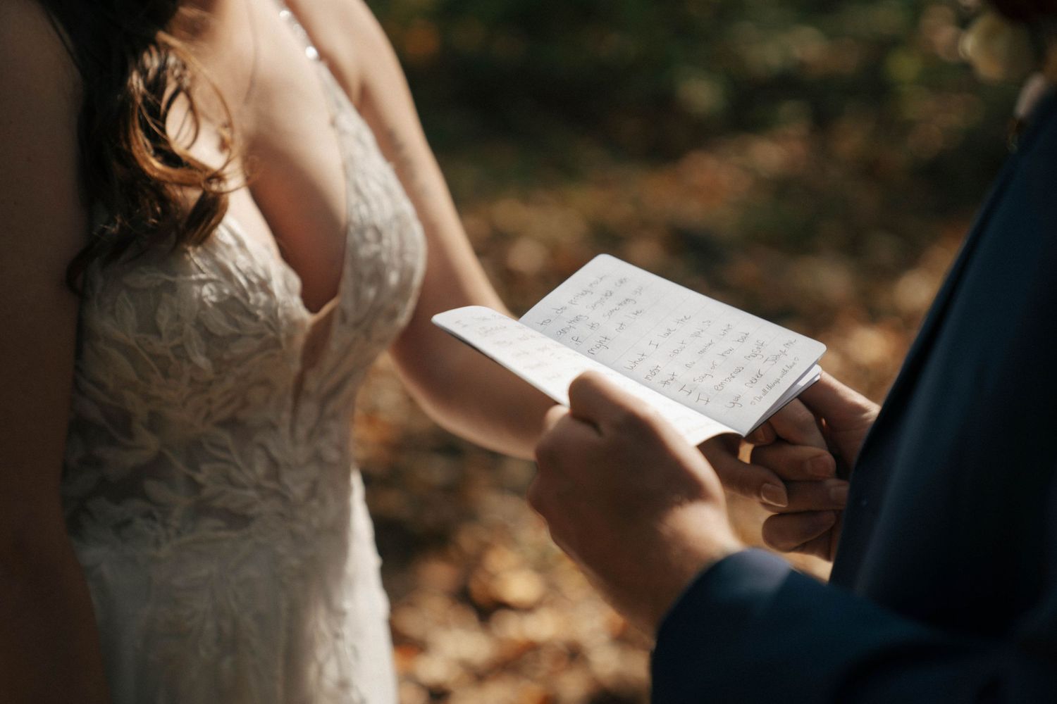 Close-up shot of hands holding wedding vows during outdoor ceremony.