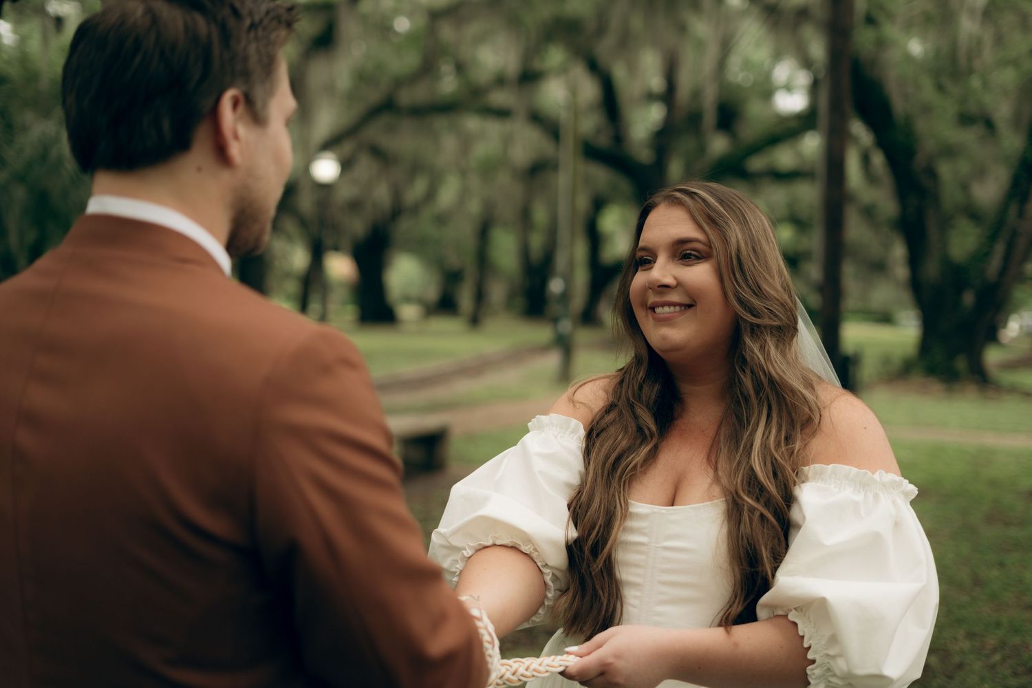 Two people share a heartfelt moment during an outdoor wedding ceremony in a lush garden setting.