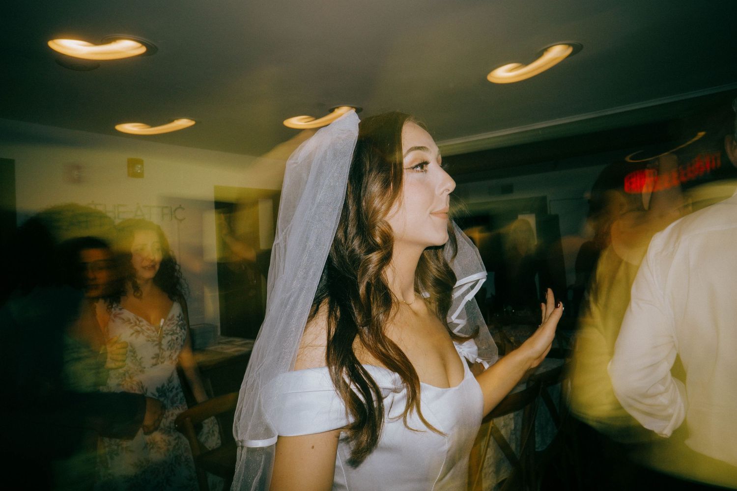 Bride in white dress and veil dances joyfully at her wedding reception.