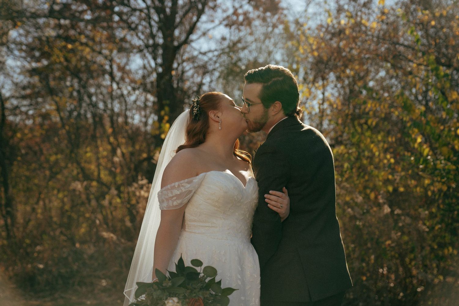 Romantic autumn wedding portrait with fall foliage in background.