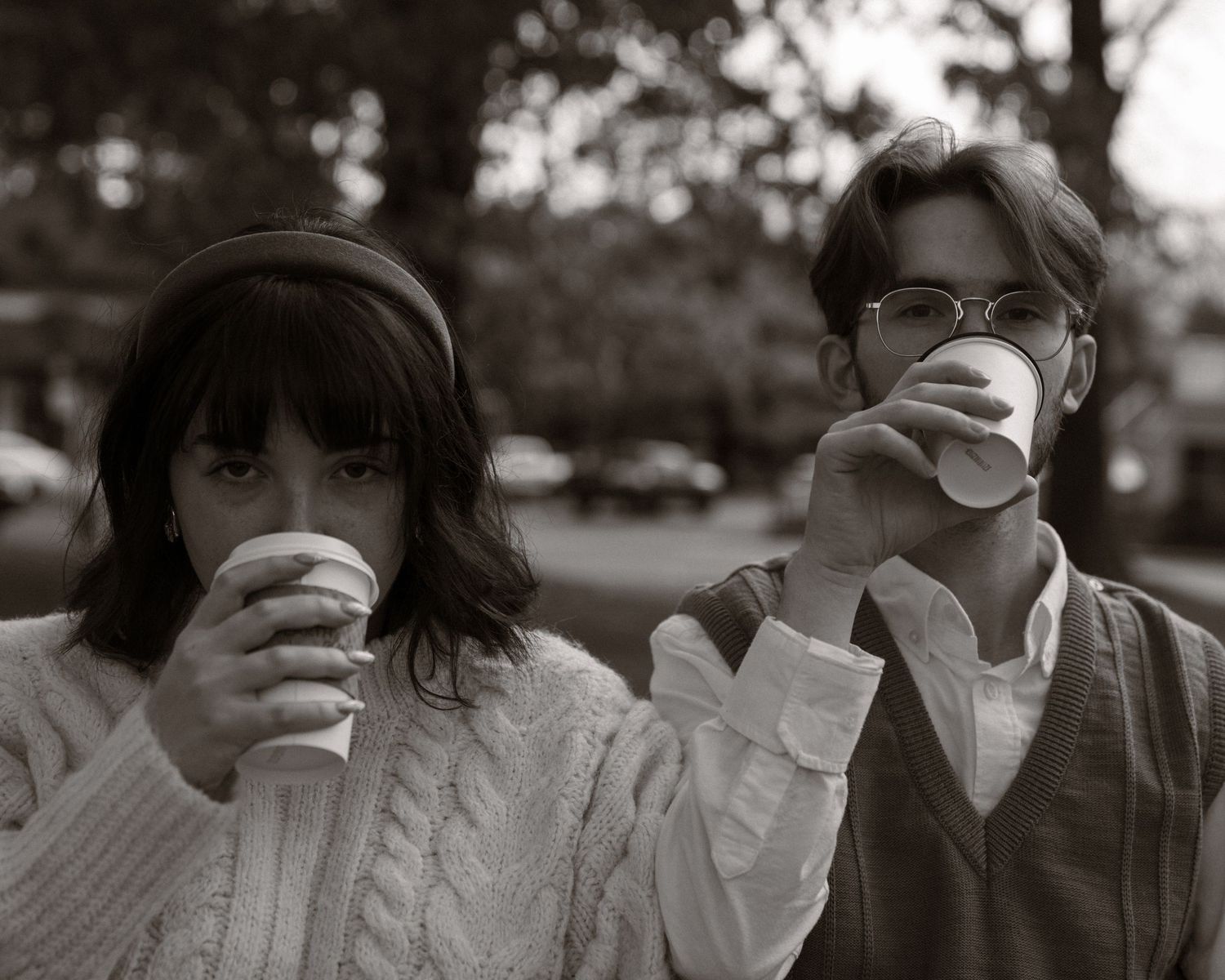 A black and white photograph shows two people drinking from paper cups outdoors - Bar Harbor Maine