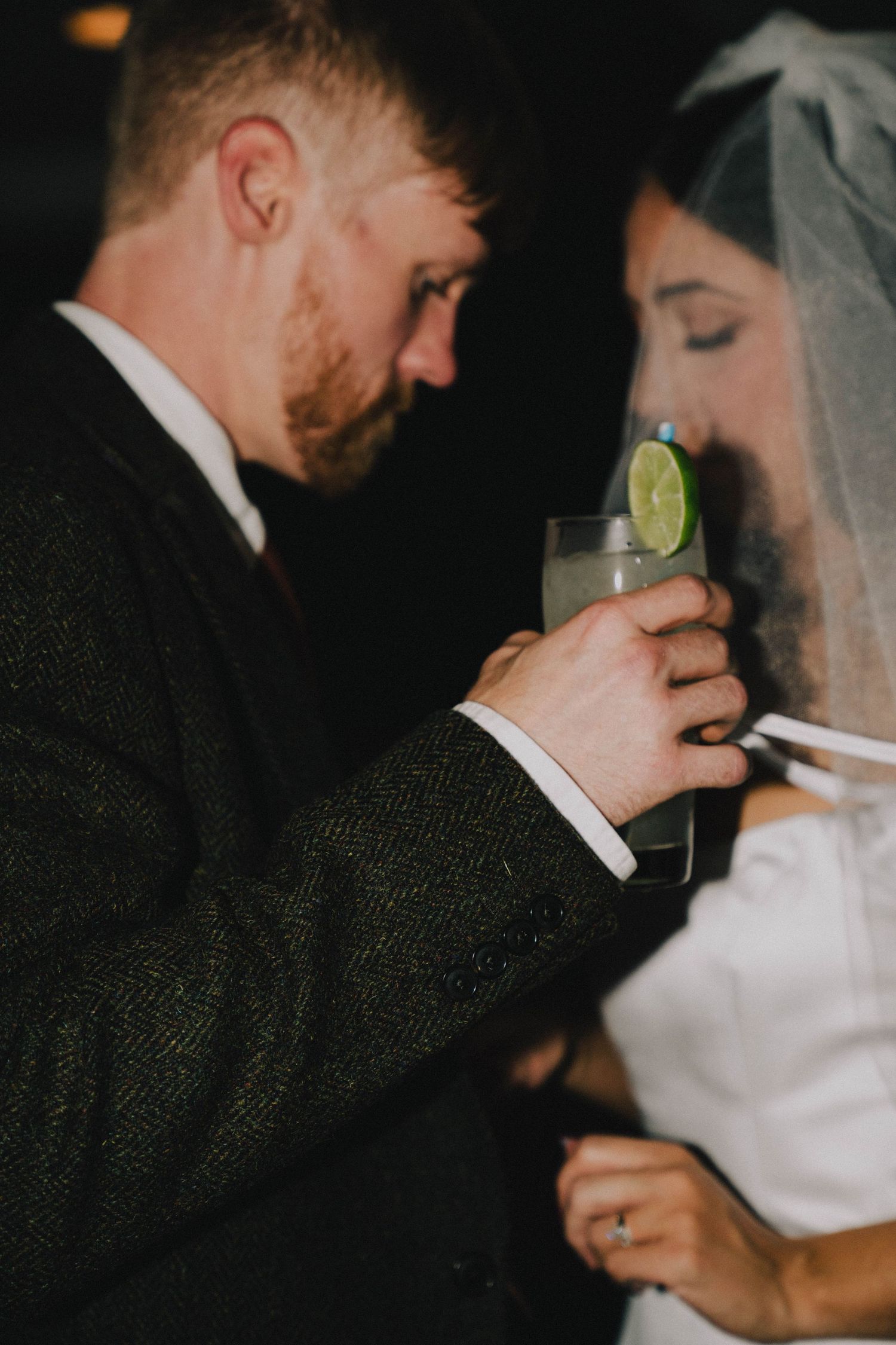 Close-up of couple sharing drinks garnished with lime at their wedding reception.