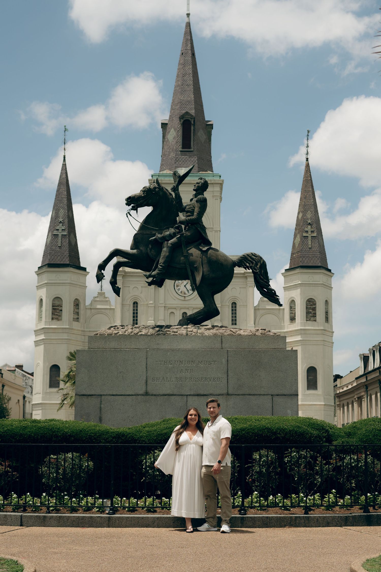 A couple stands in front of the iconic Andrew Jackson statue and St. Louis Cathedral in Jackson Square, New Orleans.