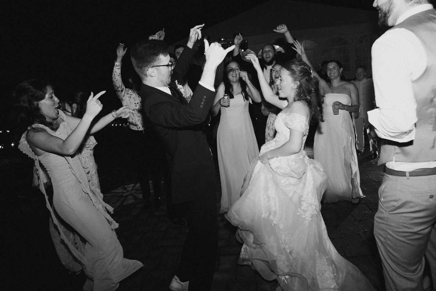 Wedding guests dance and celebrate on the dance floor at a lively black and white reception party.