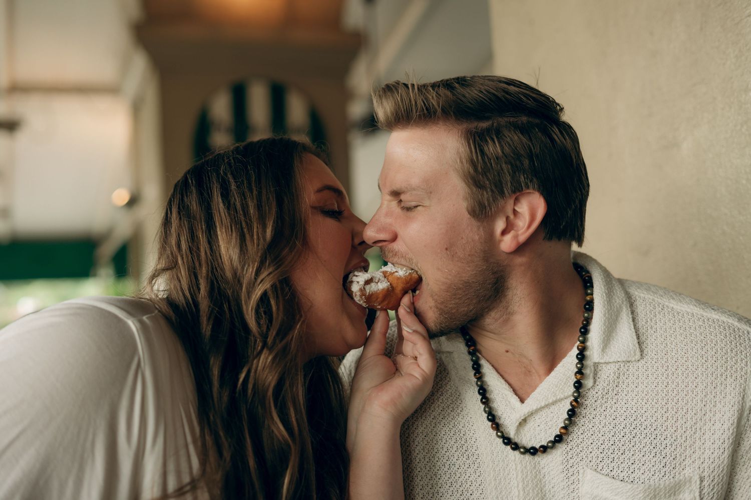 Couple sharing a sweet moment while one tenderly feeds the other a bite of food on a couch.