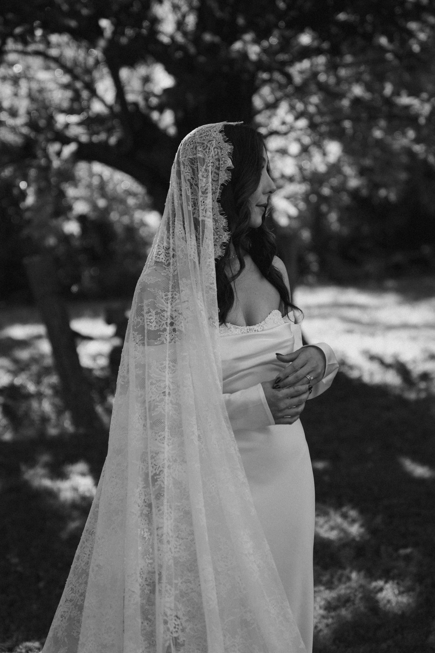 Black and white portrait of bride in lace veil and elegant wedding dress.