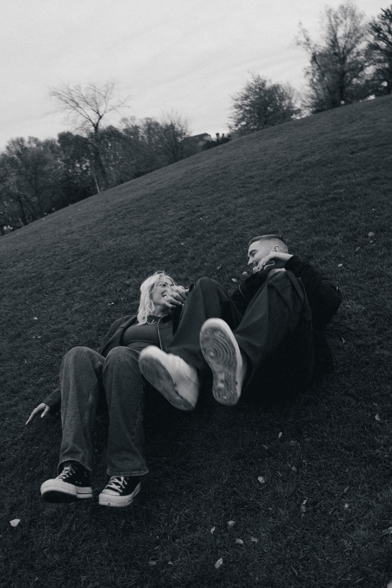 Black and white photo of someone lying down on a grassy hillside wearing casual attire. Couple in Bar Harbor Maine