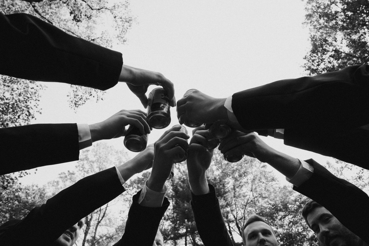 Black and white overhead view of hands joining together in a circle.