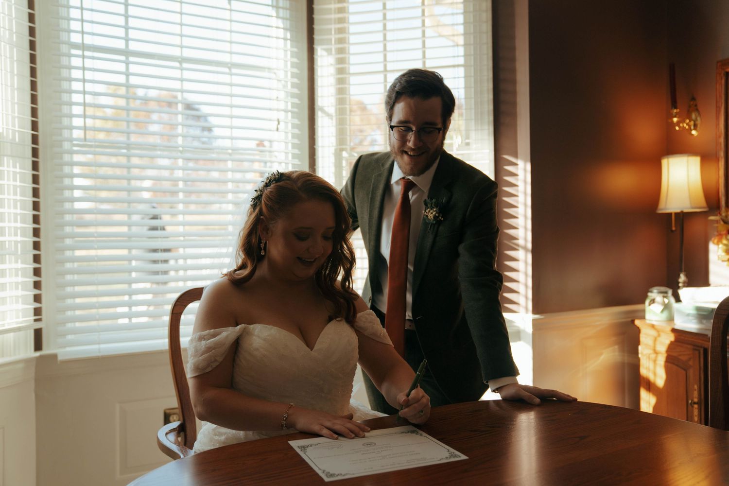 A quiet moment indoors as documents are signed at a desk near a window.