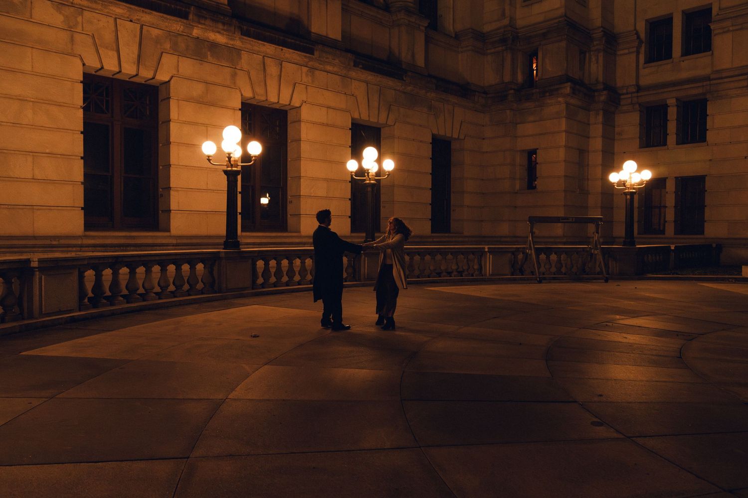 Ornate historic building interior with marble columns and glowing antique light fixtures illuminating a grand corridor.