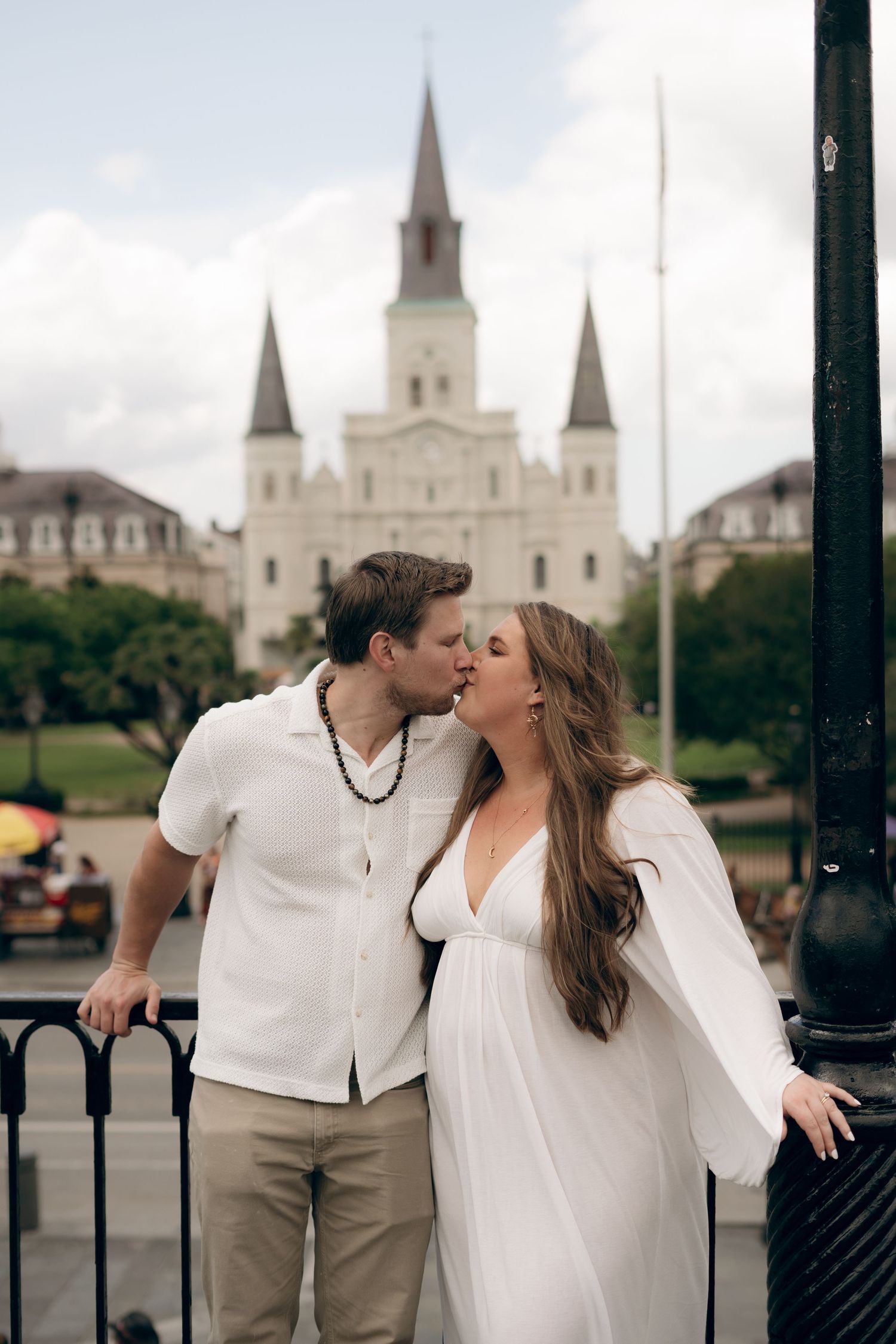 A romantic couple shares a kiss in front of the iconic St. Louis Cathedral in New Orleans' Jackson Square.