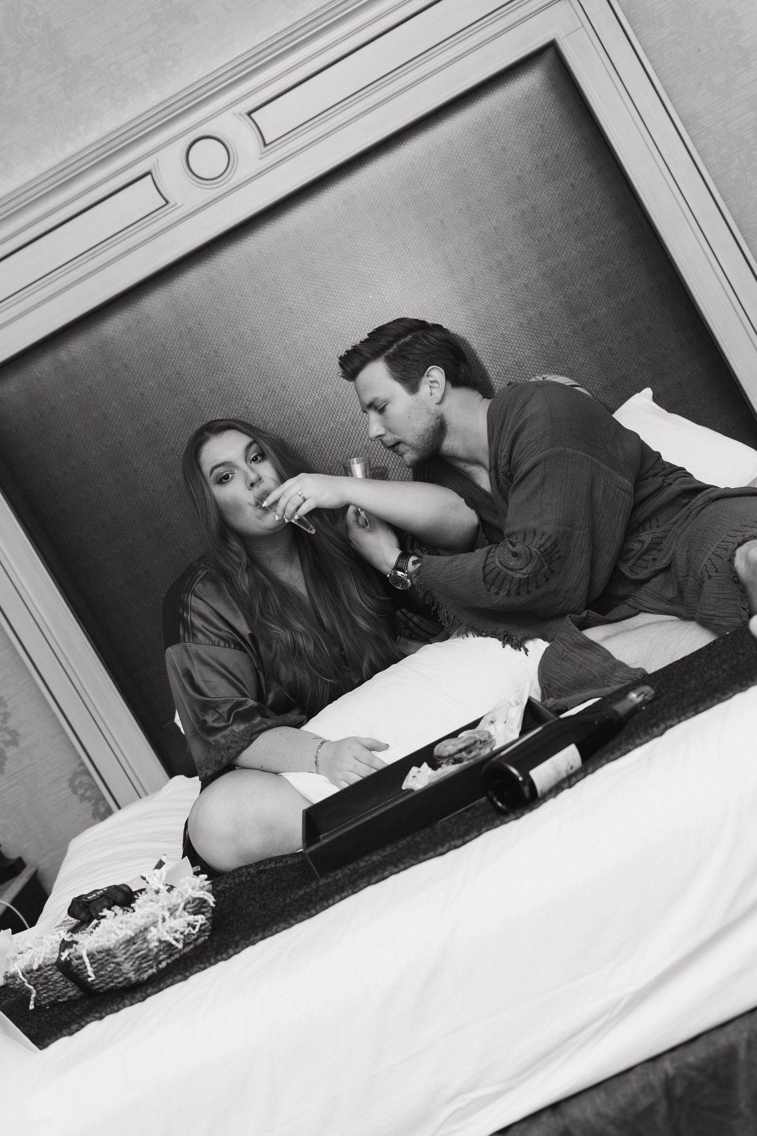 A black and white artistic photo showing two people lounging together in an intimate moment in a small space.