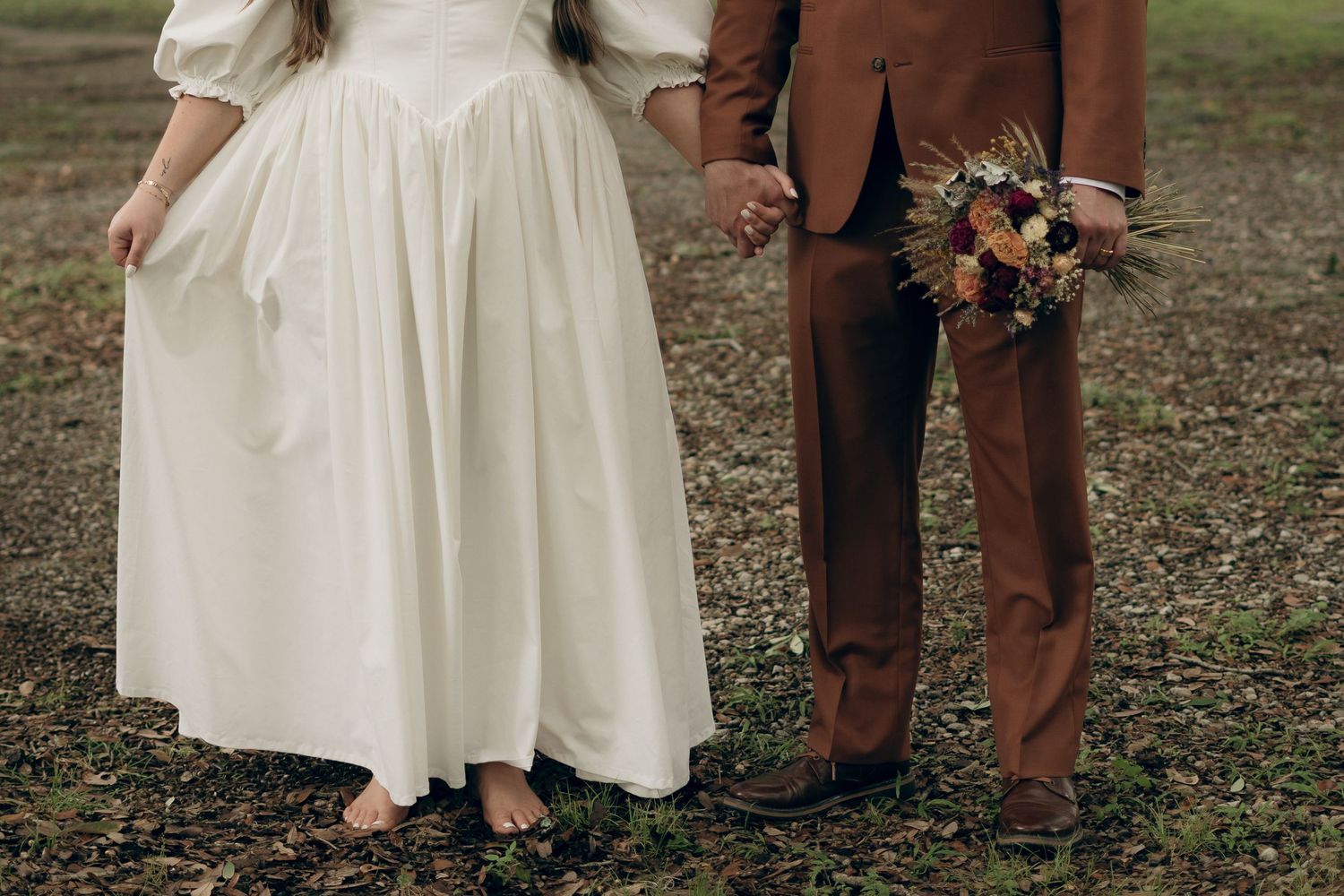 Detail shot of wedding attire showing white dress and brown suit with autumn bouquet.New Orleans