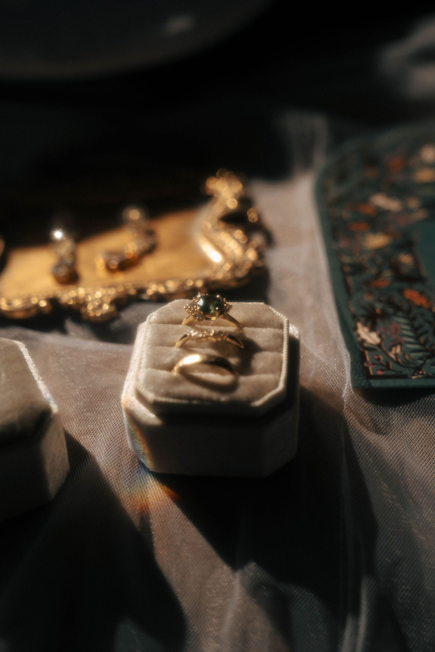 Close-up of vintage-style jewelry boxes and accessories on textured fabric.
