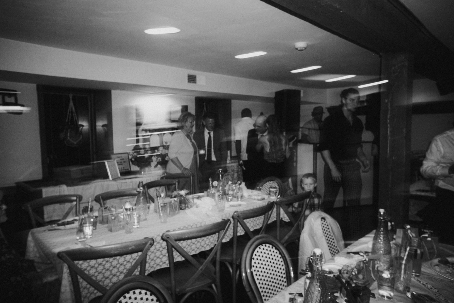 Black and white photo of an elegant wedding reception setup with tables and place settings.