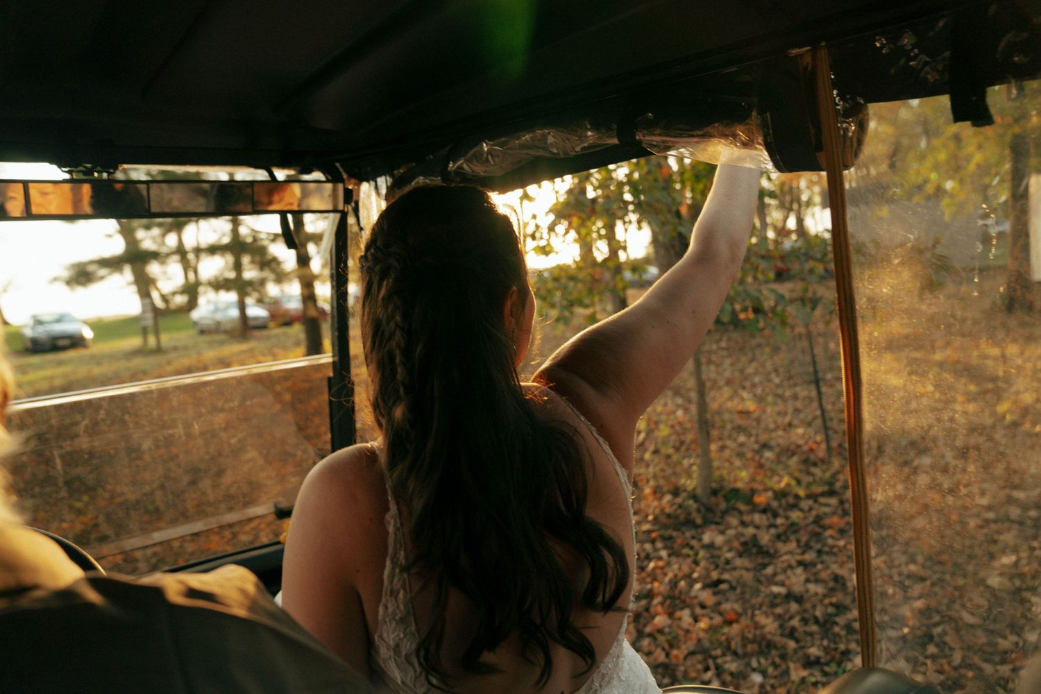 White dress in soft evening light reaching out from inside a vintage vehicle.
