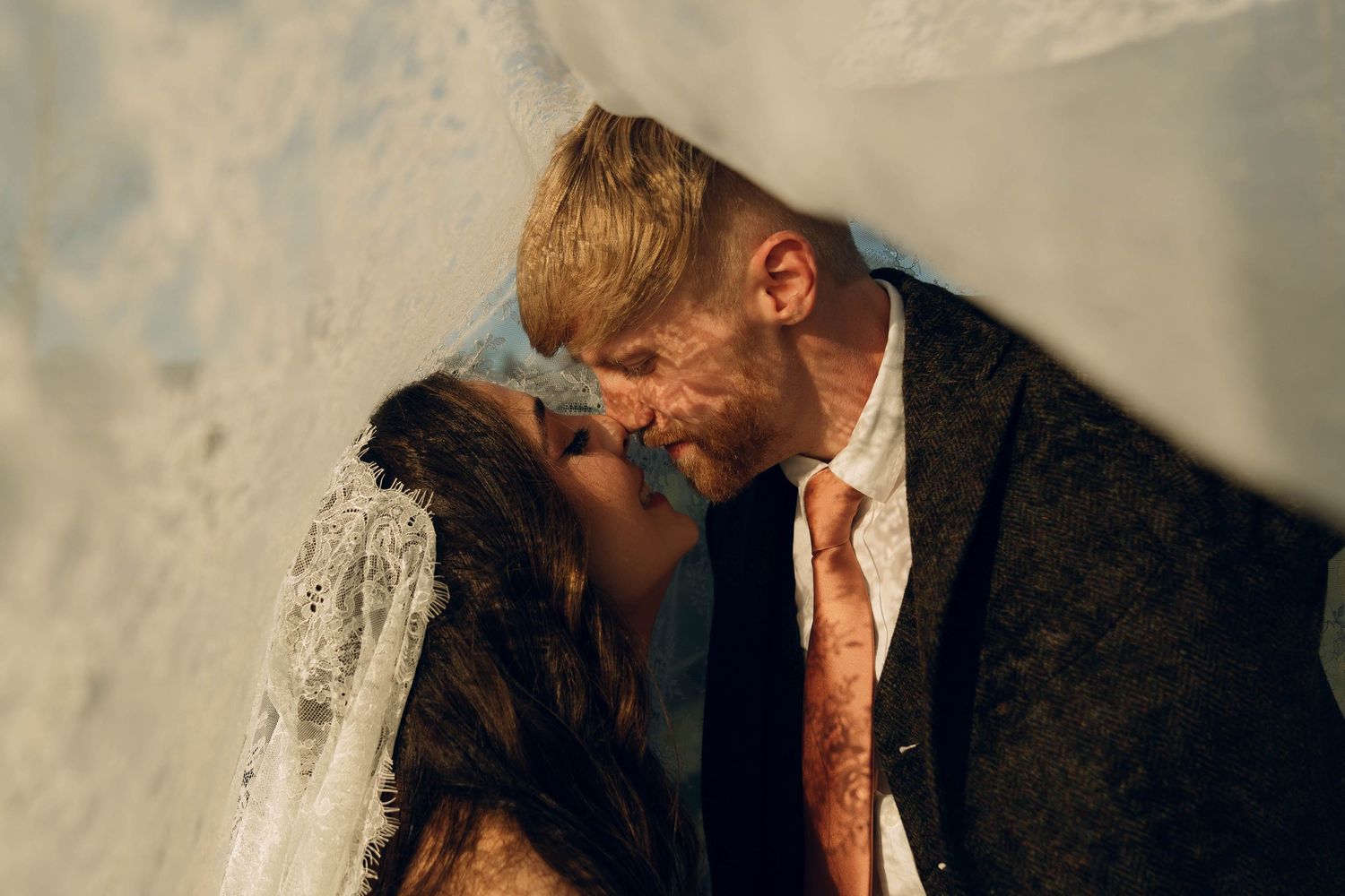 Intimate moment between newlyweds captured in golden sunlight.