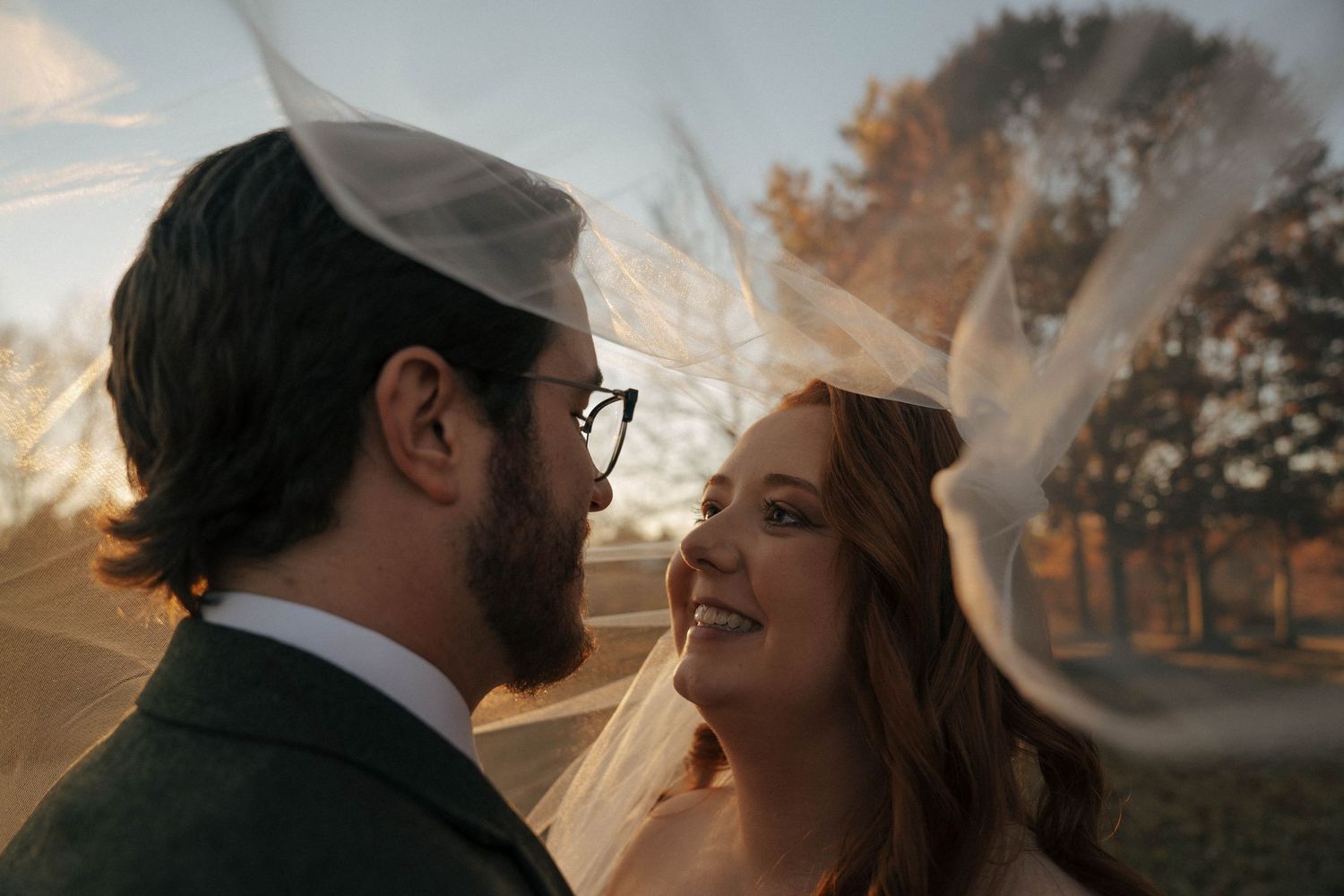 Wedding couple shares an intimate moment at golden hour with sunlight streaming through trees.