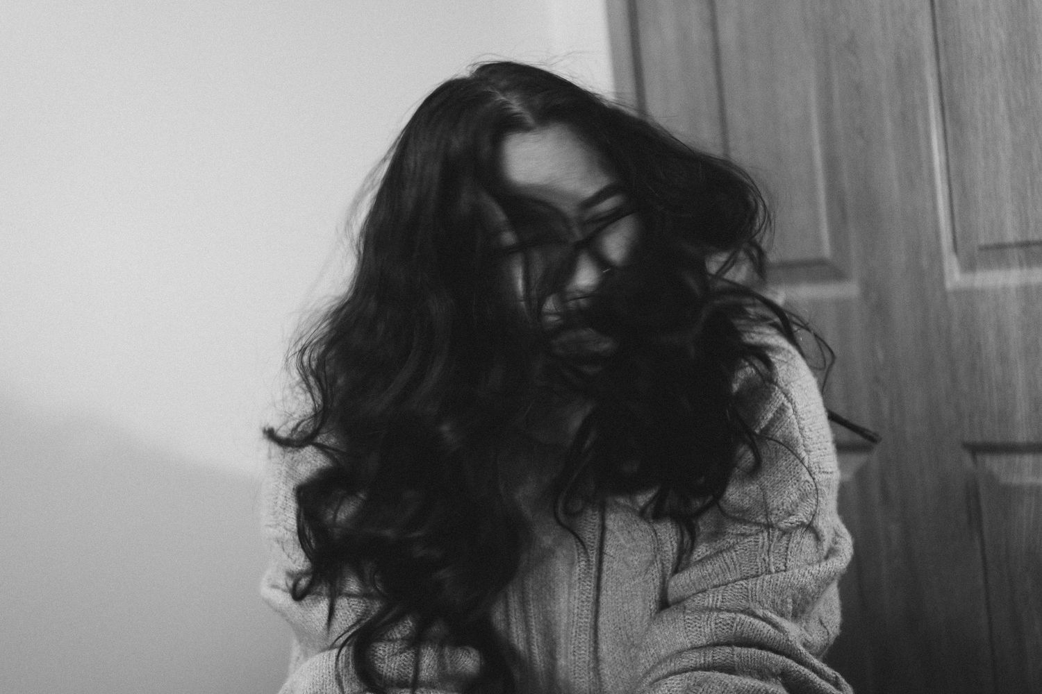Artistic black and white portrait showing flowing dark hair and sweater.