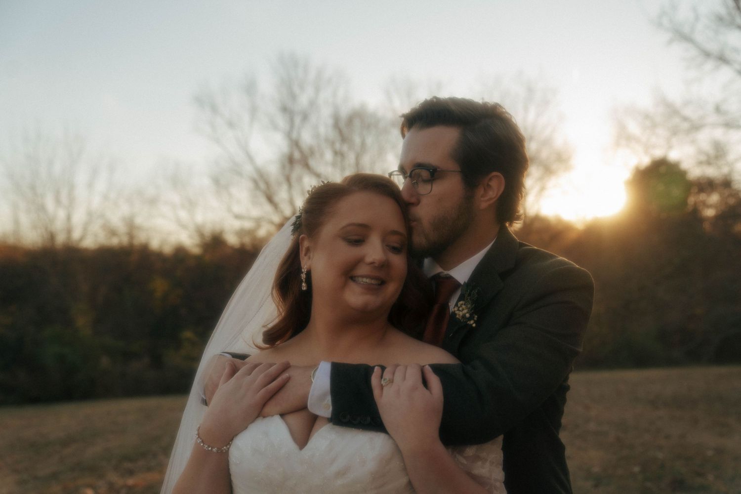 Intimate wedding moment captured at sunset as a couple shares a tender embrace outdoors.