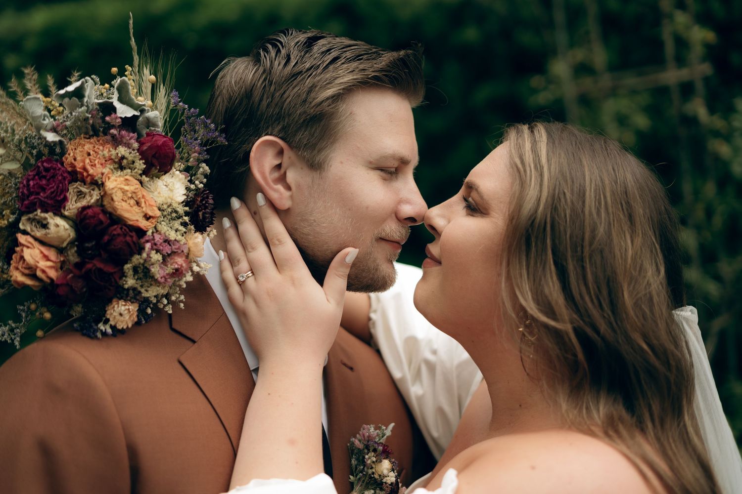 A romantic wedding moment captured between a couple, with beautiful dried floral arrangements in warm autumn tones.