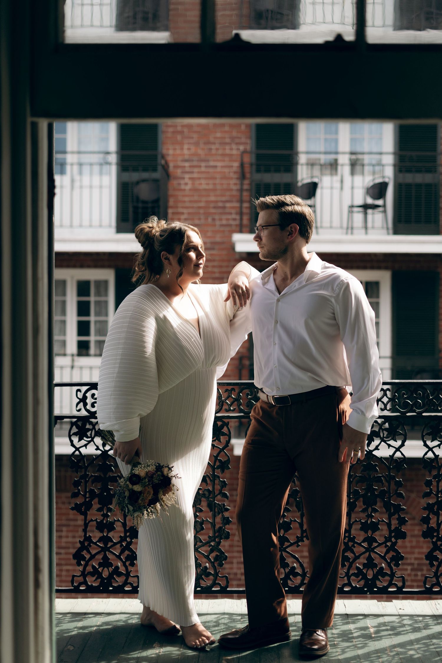 Couple in white and black attire shares romantic moments across three connected frames on a balcony with decorative railings.