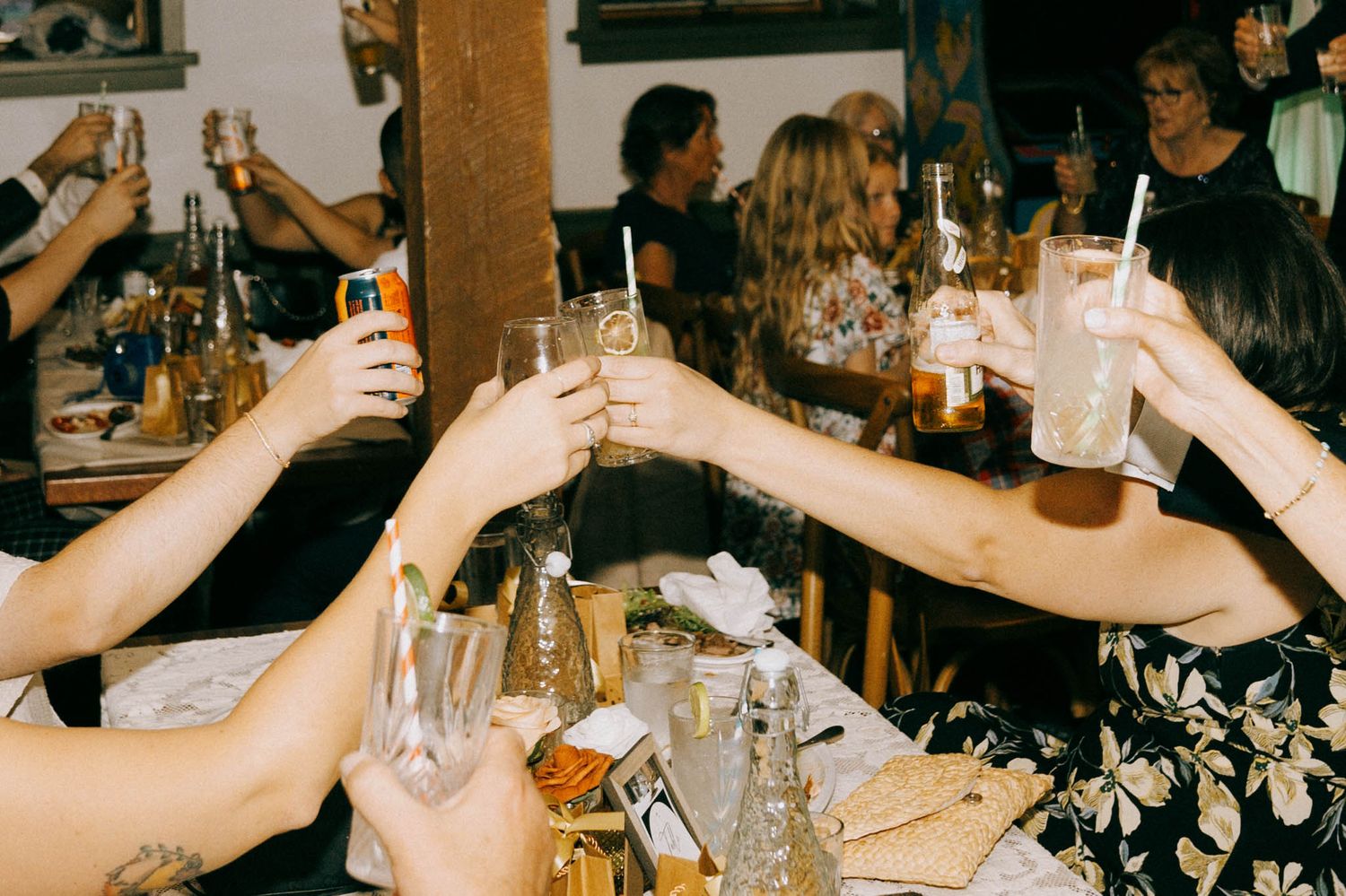 Friends raise their glasses in a celebratory toast at a wedding reception.