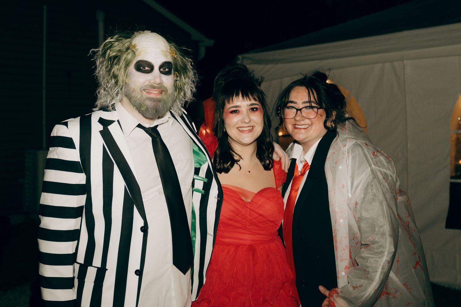 A group of people pose together wearing black and white striped suits and red dresses at a formal event.