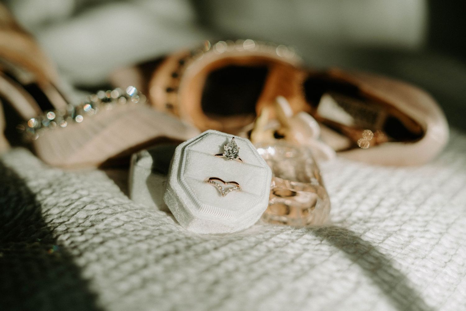 Close-up of wedding rings and jewelry arranged on white textured fabric.