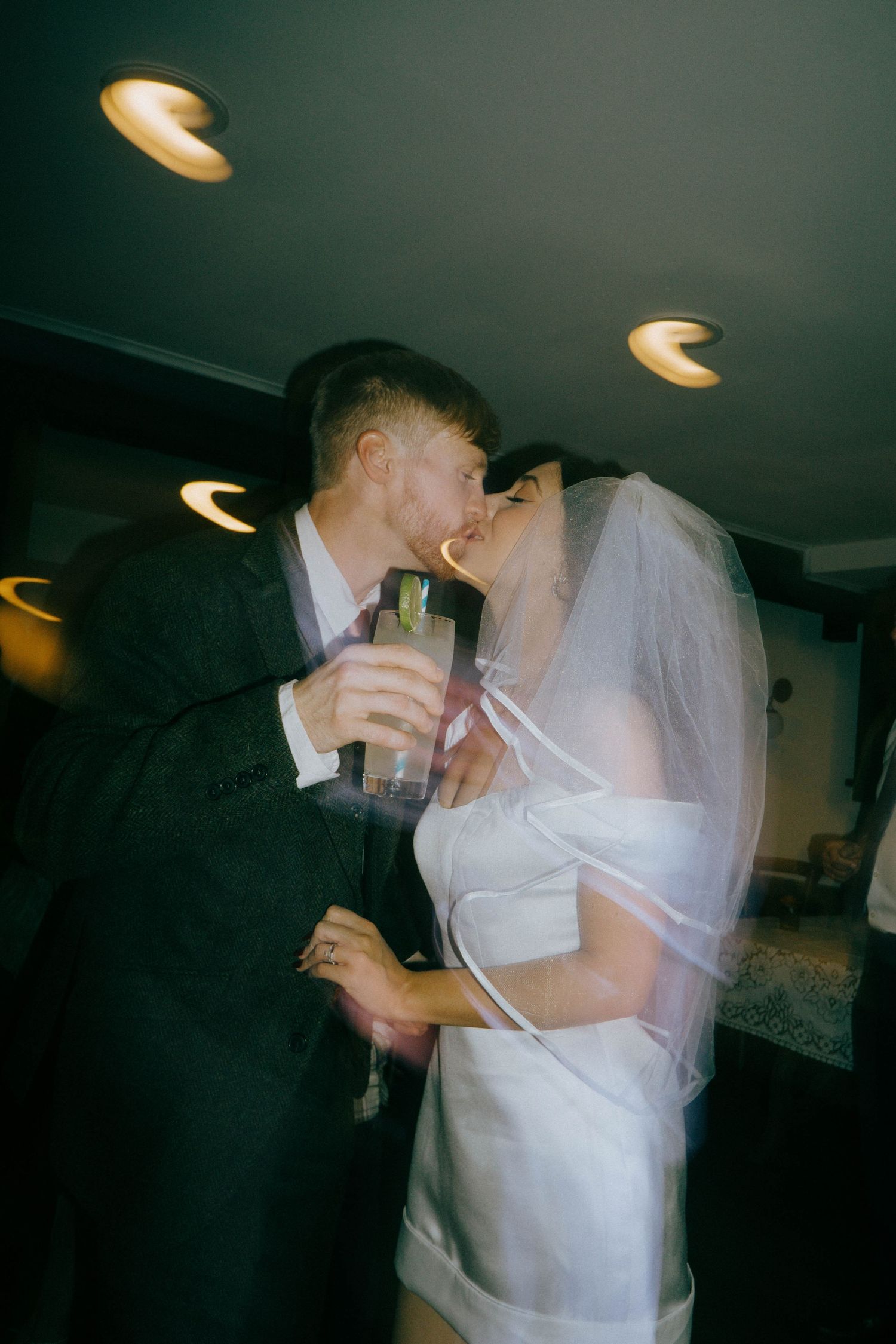 Wedding couple shares a romantic moment while holding drinks at their reception.