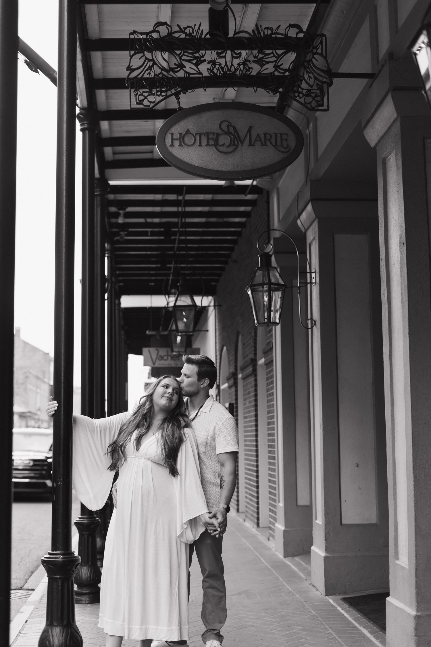 A couple shares a tender moment beneath the vintage Hotel Marie signage and covered colonnade.