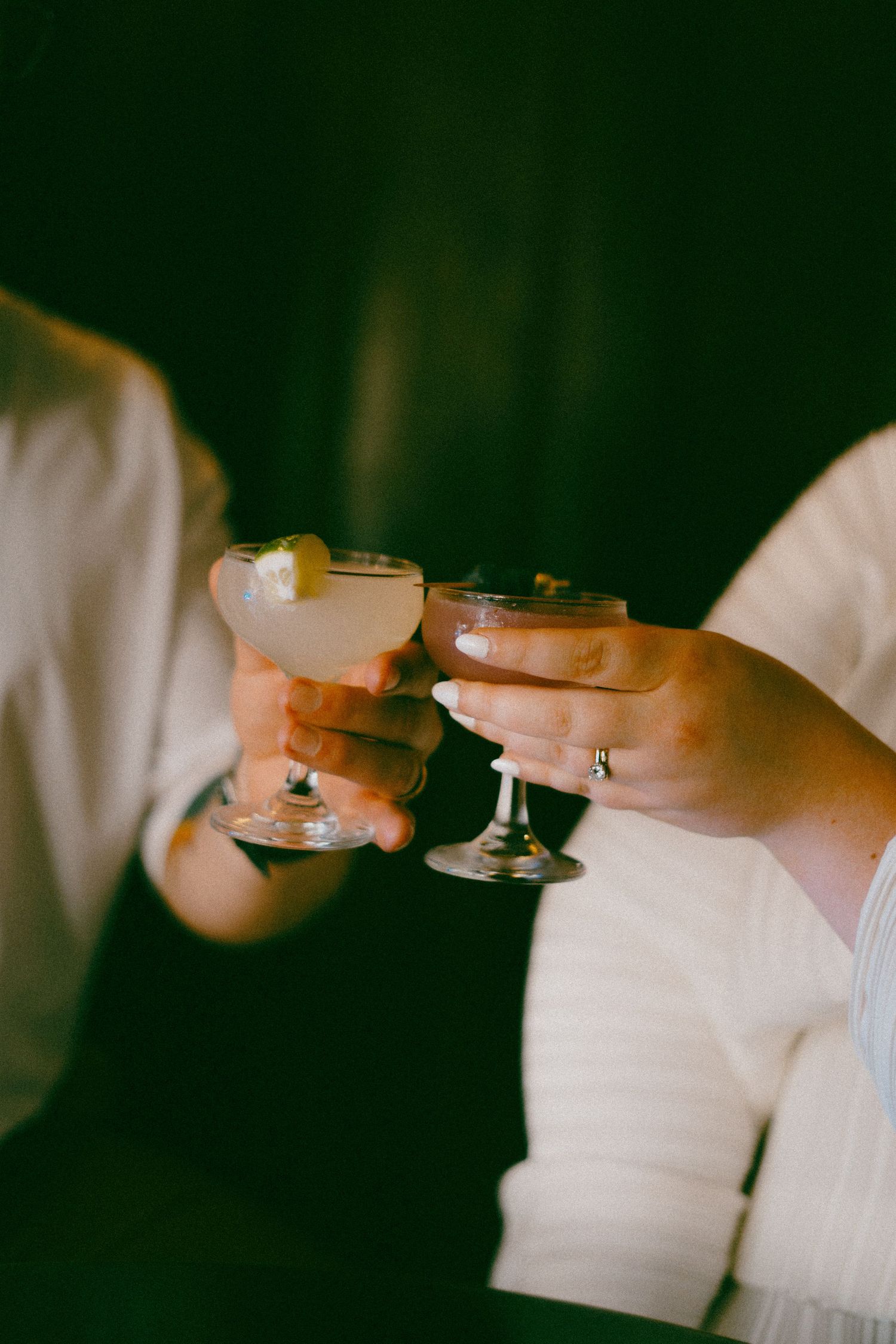 Multiple hands holding champagne glasses against a dark background in a synchronized toast motion. New Orleans