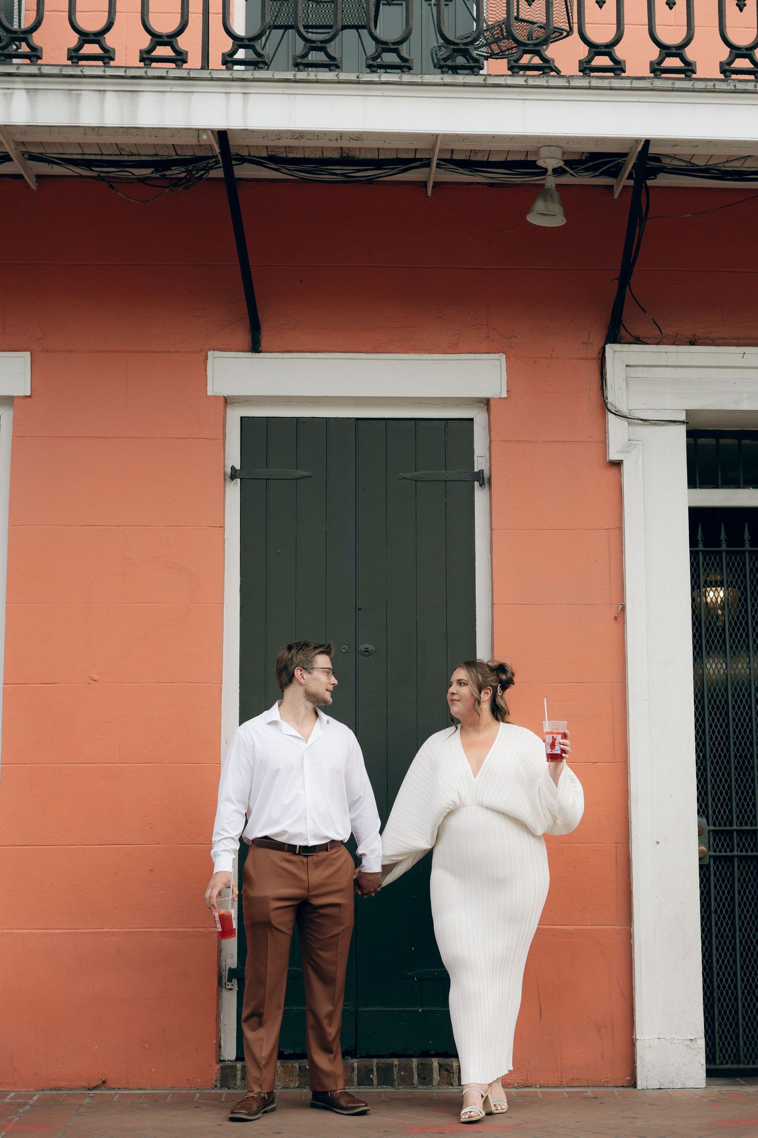 People enjoying a festive moment in a historic French Quarter courtyard with coral-colored walls and white trim.