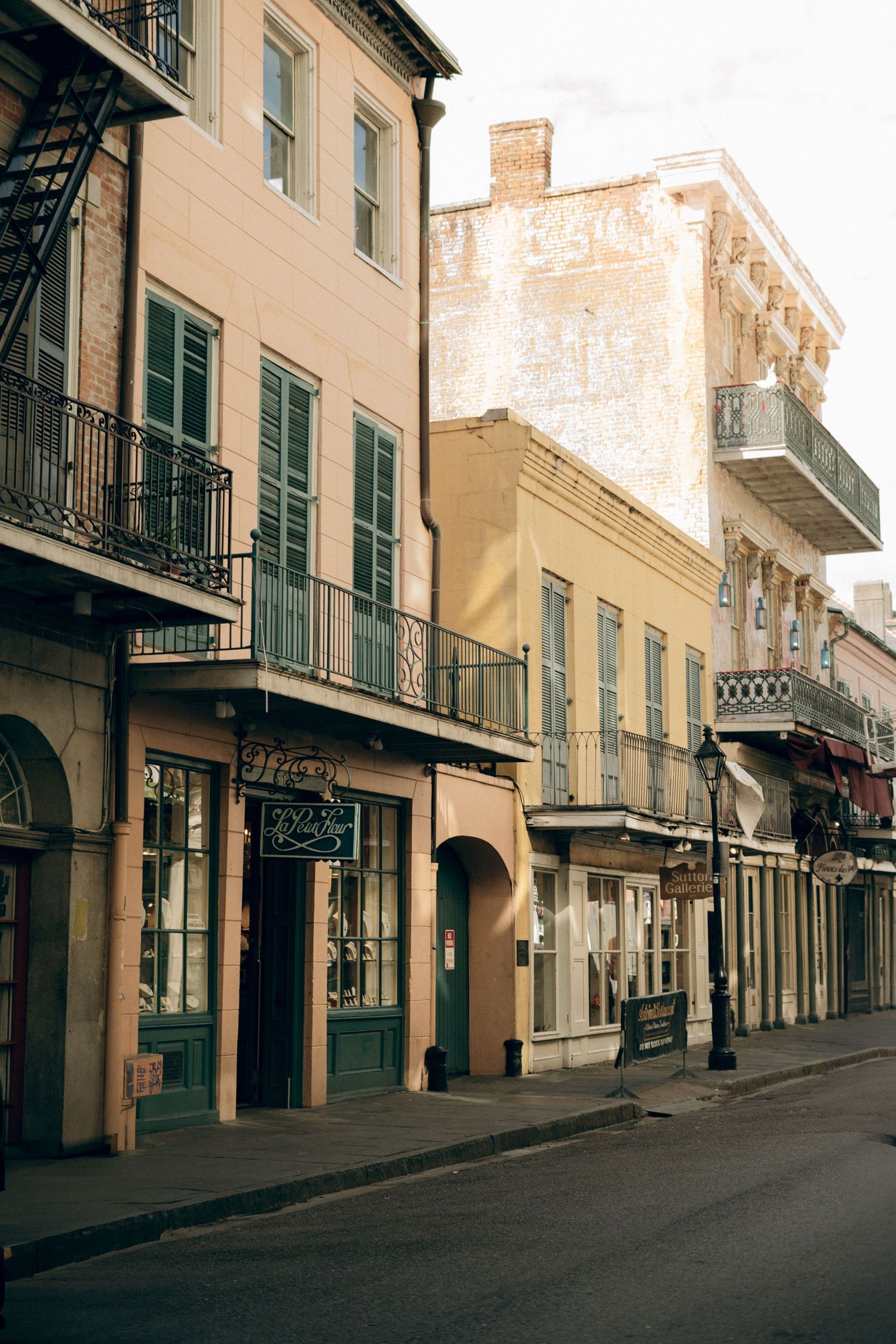 Historic buildings with ornate balconies and shutters line a street in New Orleans' French Quarter.