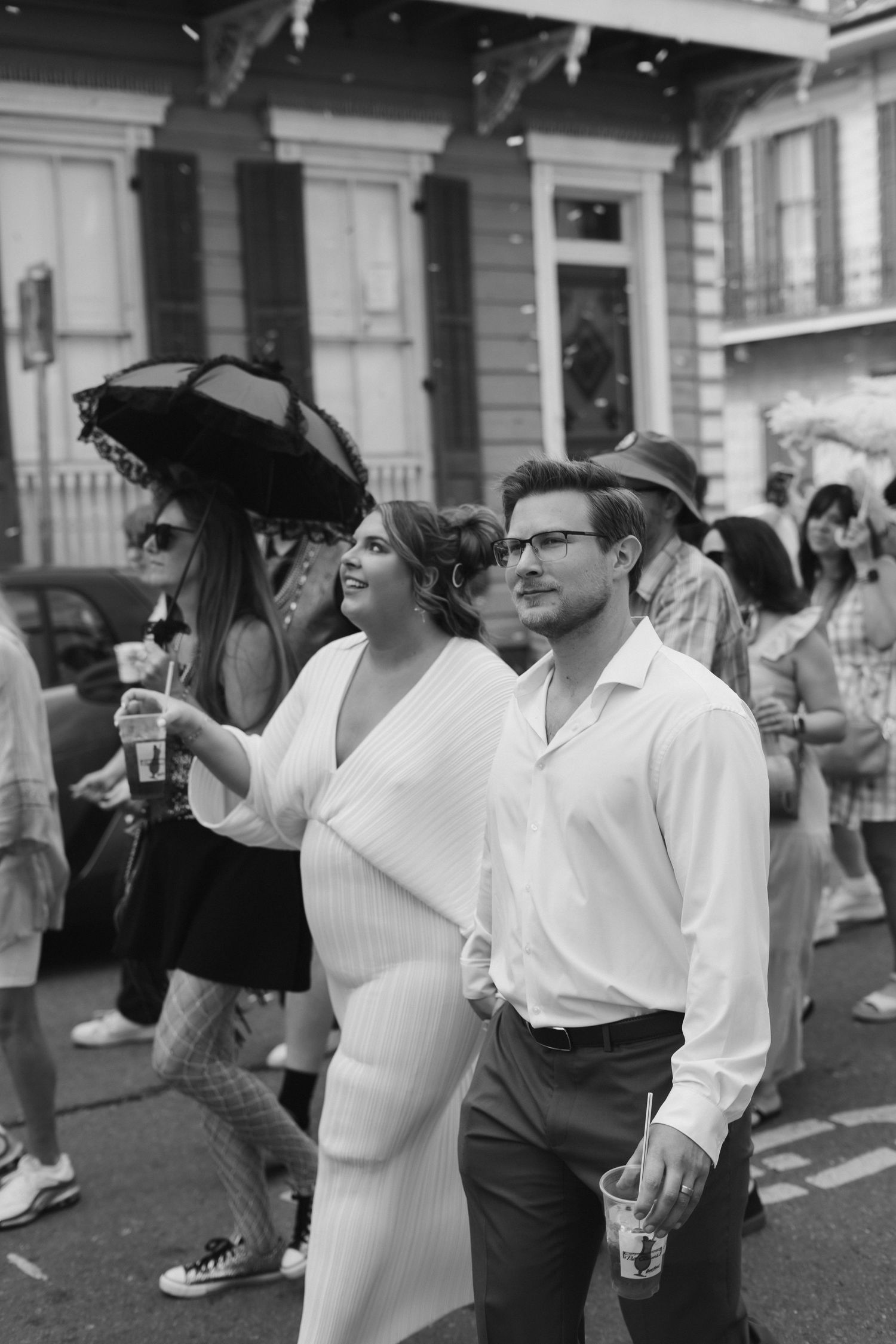 A group of people in white attire raise their glasses in a celebratory toast at an outdoor gathering. New Orleans