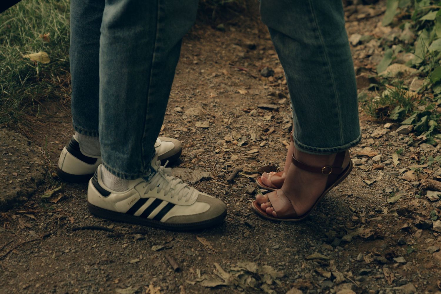 Close-up view of feet of hikers on dirt trail wearing athletic shoes and boots.