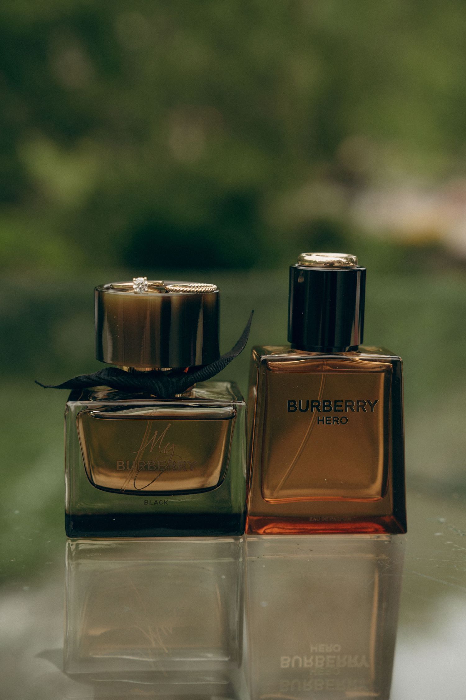 Two elegant Burberry perfume bottles displayed on reflective surface with soft focus background.