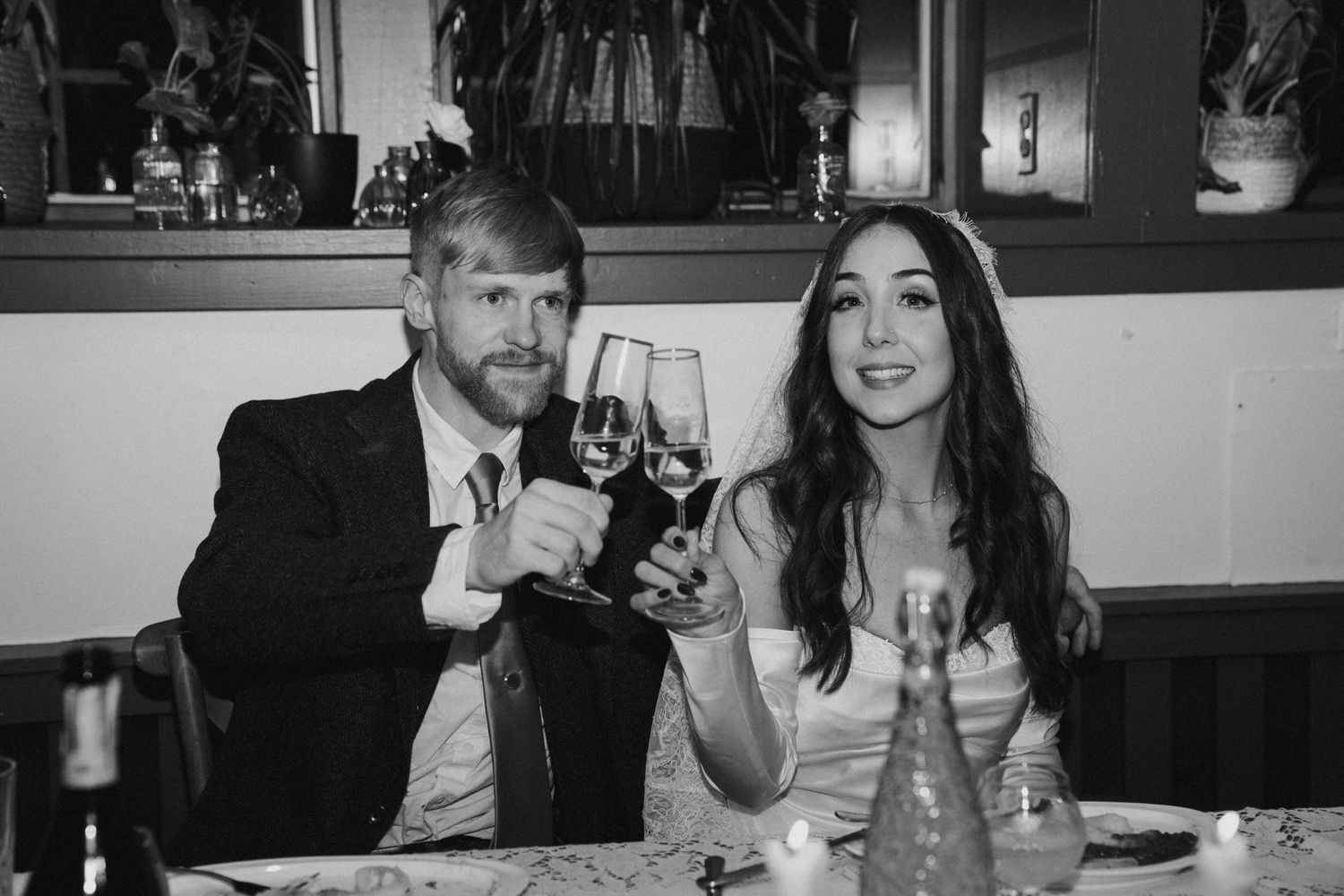 A couple raises wine glasses in celebration at their wedding reception.