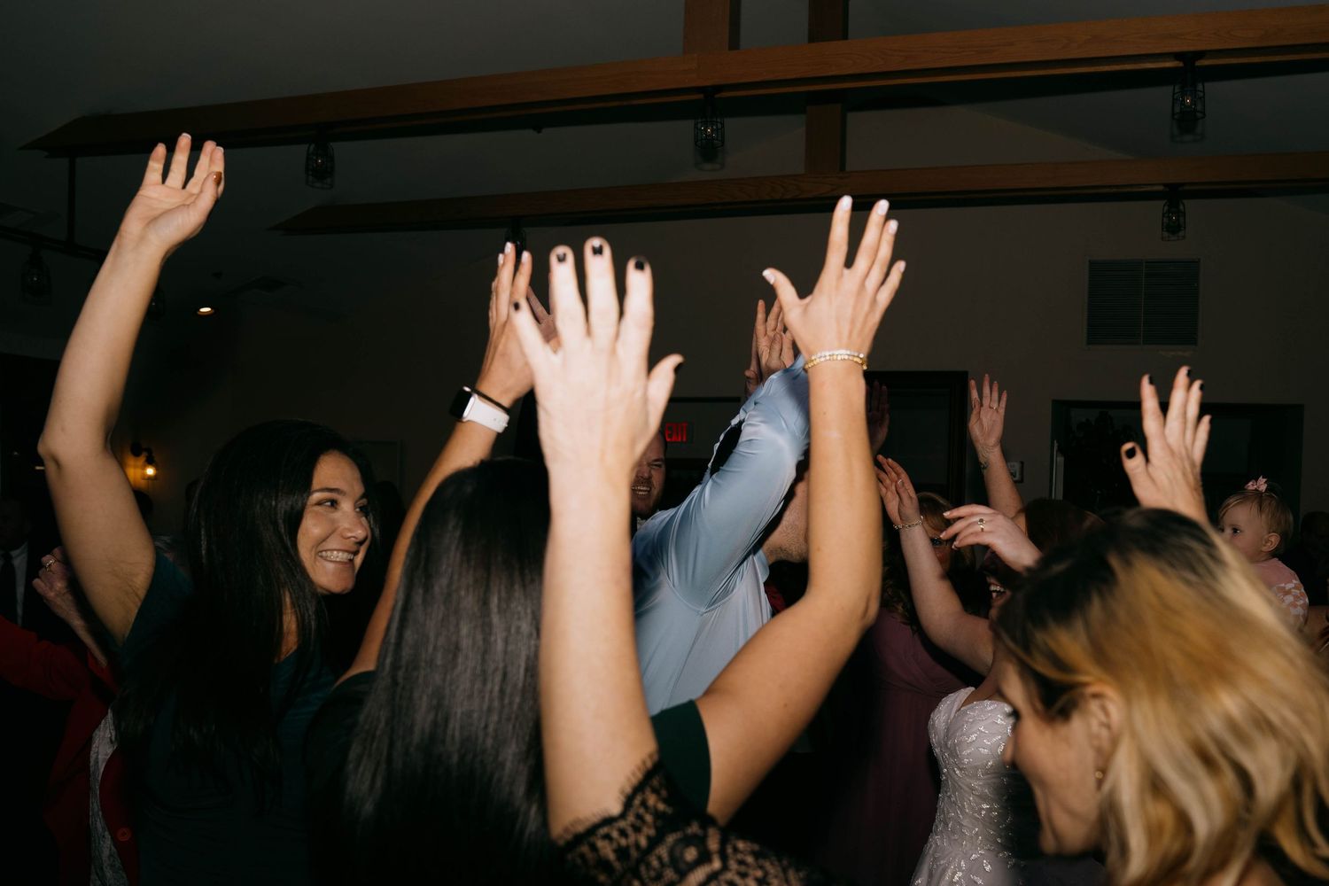 Hands raised in celebration on a dark dance floor at a party.