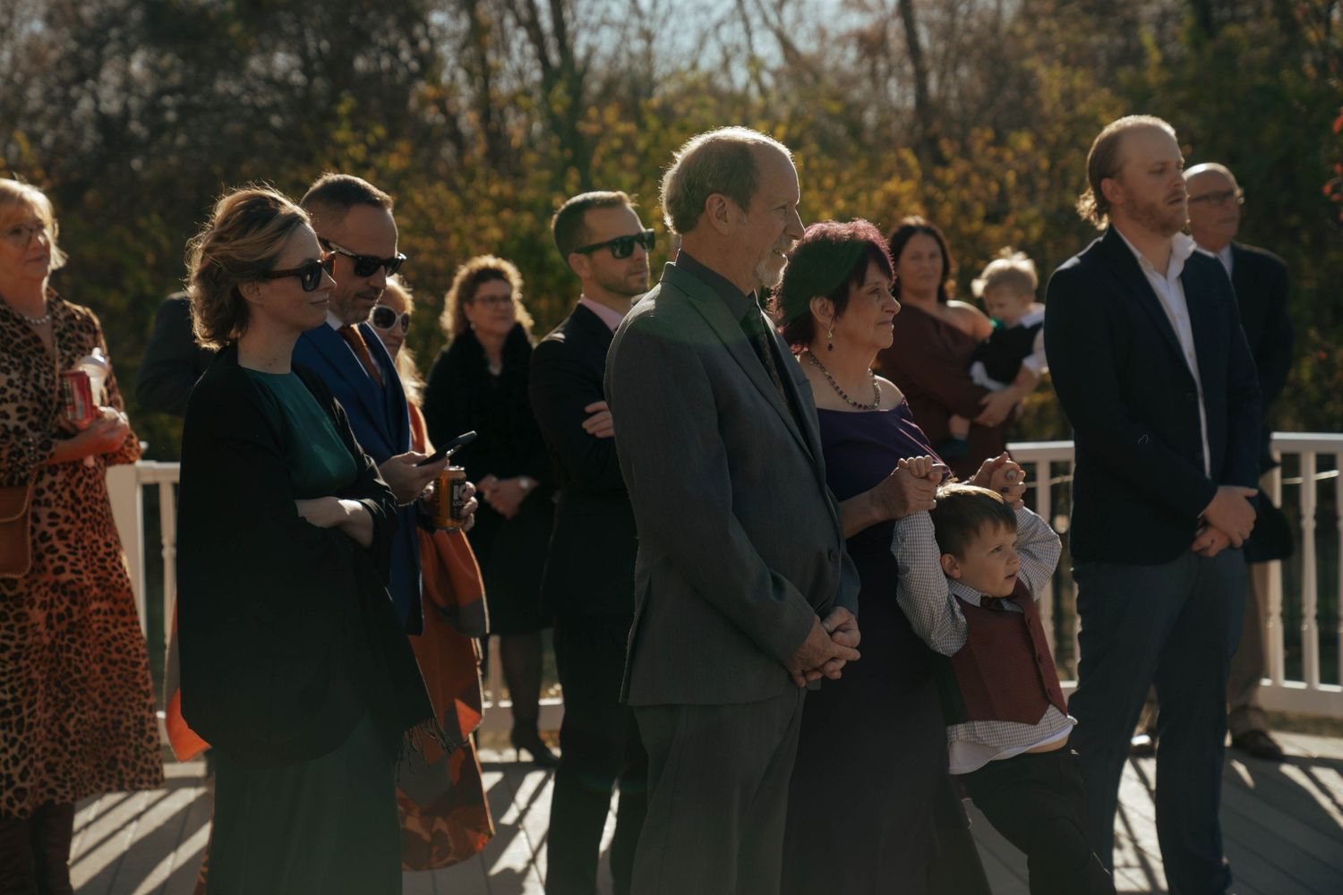 Wedding guests gathered outdoors watching a ceremony on a sunny autumn day.