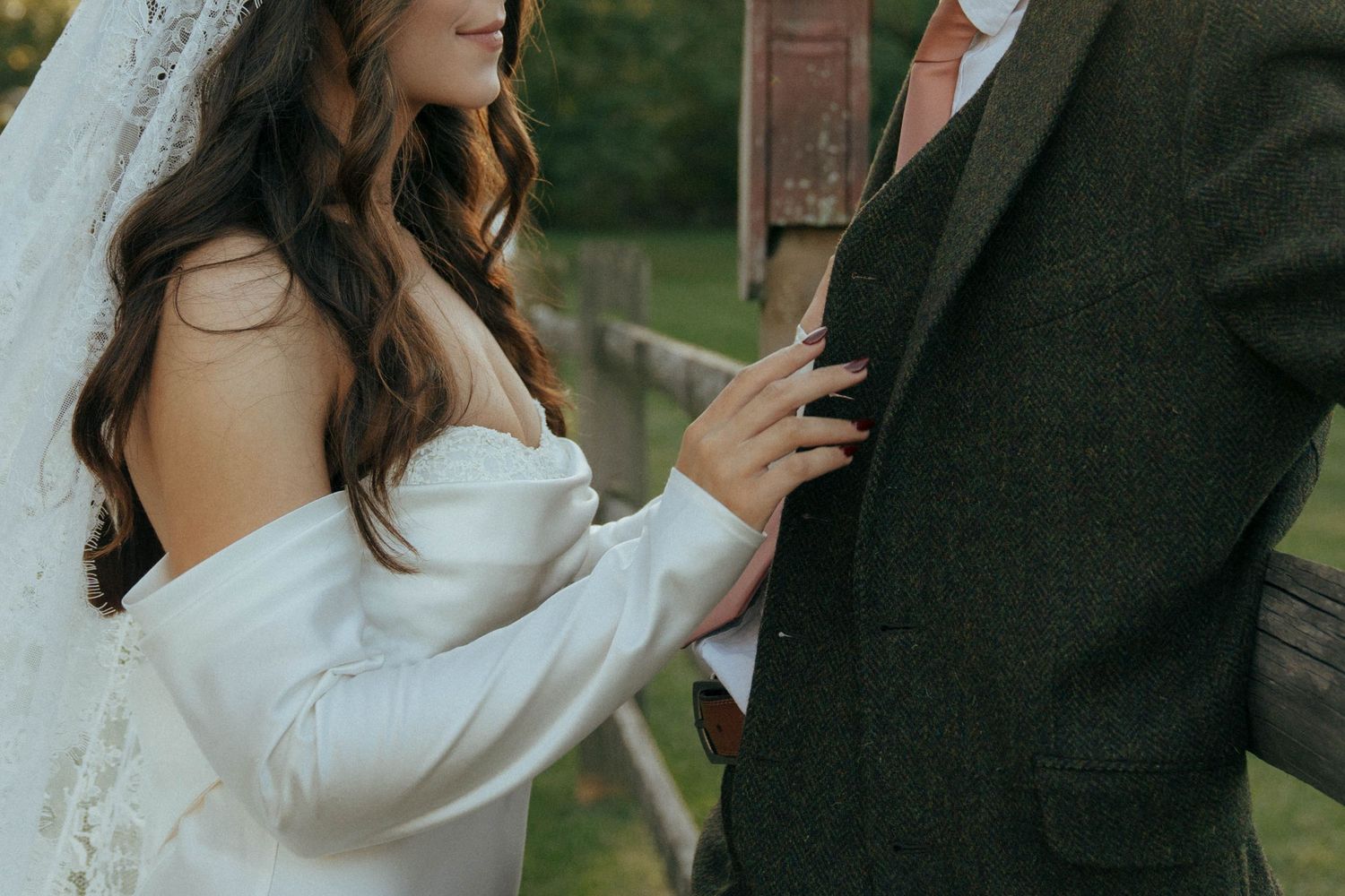 Detail shot of bride's flowing sleeve and groom's suit during intimate moment.