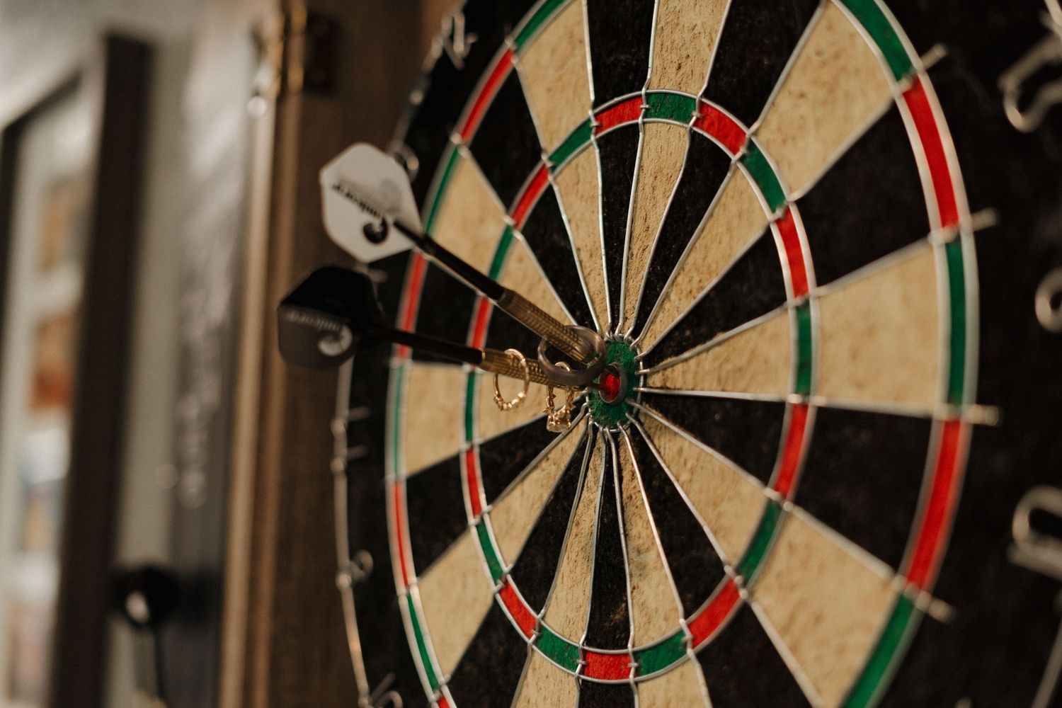 Close-up view of a classic dartboard with red and green sections mounted on a wall.