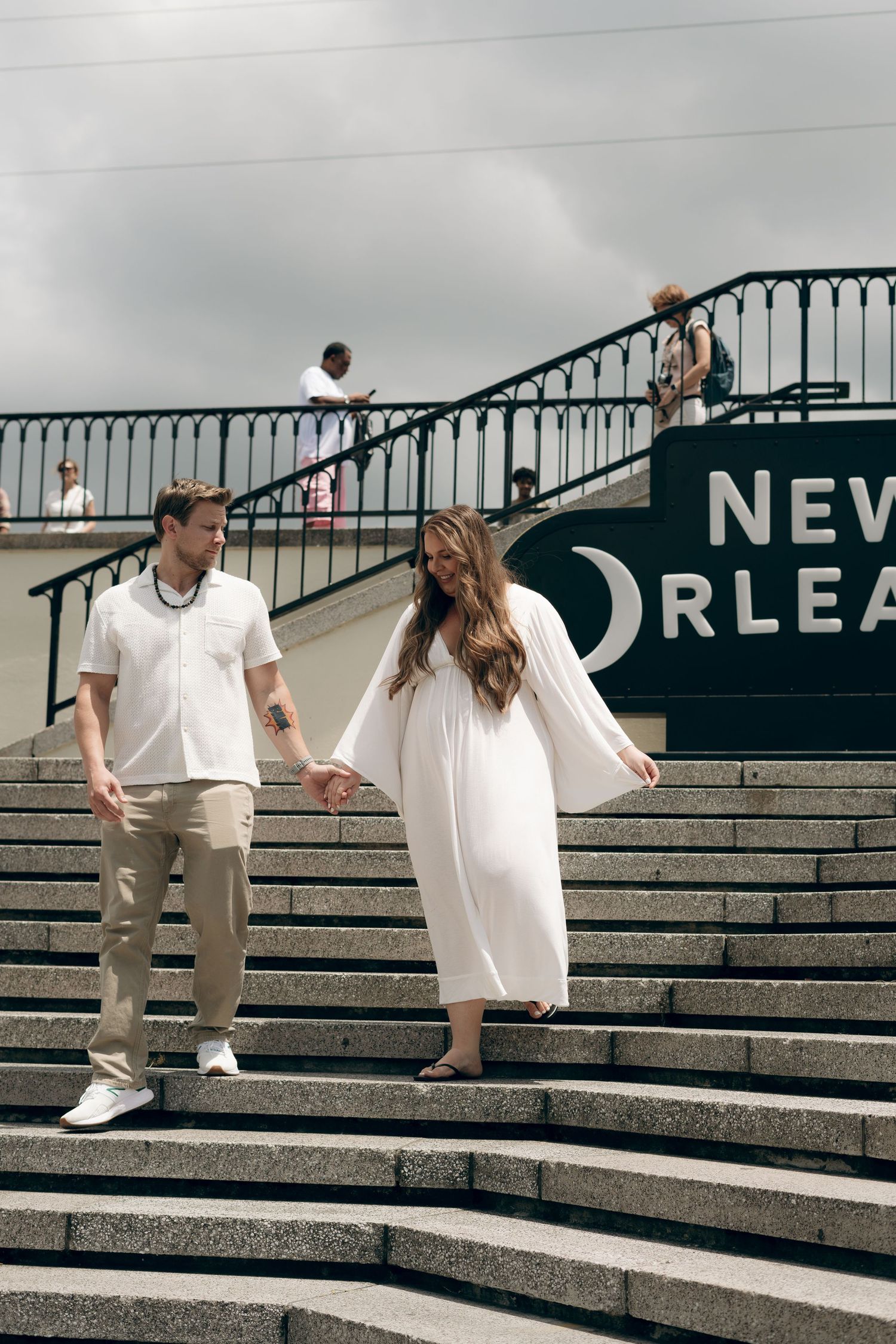 People dancing and moving playfully on concrete steps with New Orleans signage visible in the background.